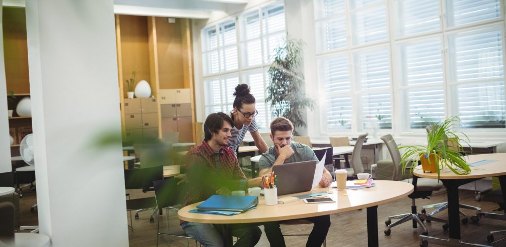 Group of business executives discussing over laptop at their desk in the office