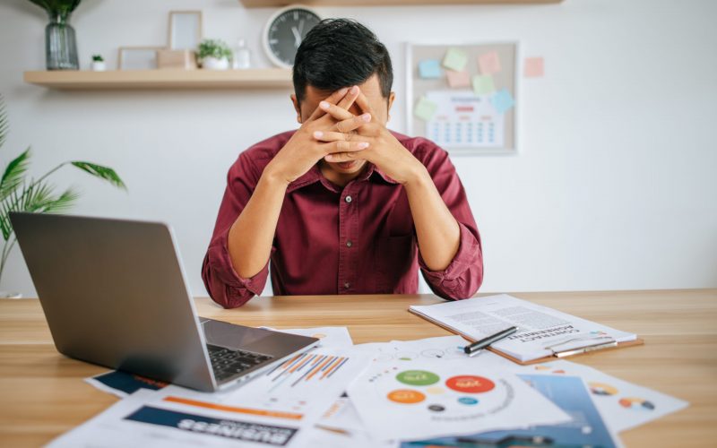 Man working with laptop and paperwork with stress